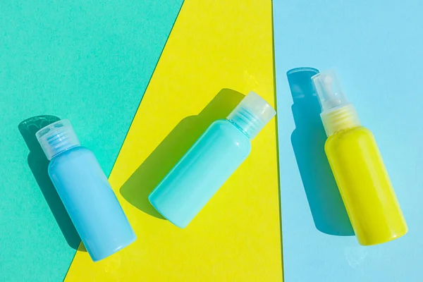 Yellow and blue cosmetic bottles on the same colored background. Stylish concept of organic essences, beauty and health products. Copy space, minimalism, flat lay.