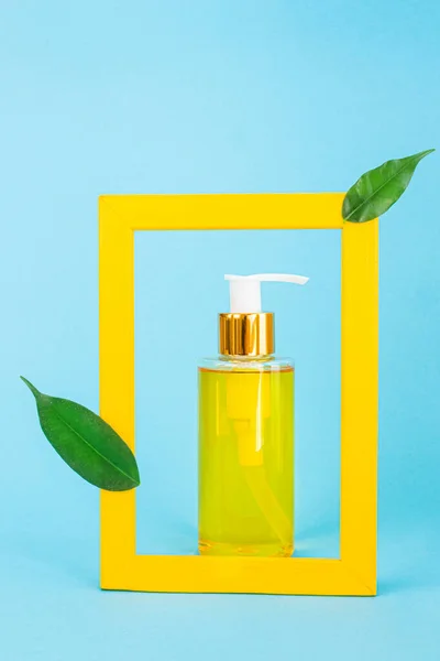 装有天然油的注射器的化妆品瓶是由一个黄色的框架构成的 那里有绿叶 有机精华 美容和保健产品的时尚概念 简约主义 复制空间 — 图库照片