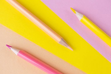 Okula dönelim. Pembe ve sarı kalemler arka planda aynı renkte yatar. Çocukların yaratıcılığının yaratıcı minimalist konsepti, çizim.