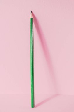 Okula dönelim. Pembe arka planda yeşil bir kalem duruyor. Çocukların yaratıcılığının yaratıcı minimalist konsepti, çizim.