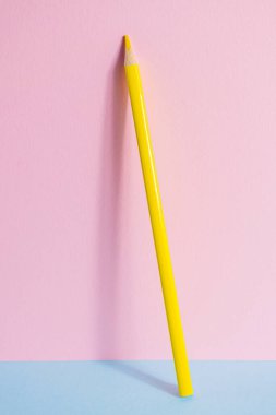 Okula dönelim. Pembe-mavi arka planda sarı bir kalem duruyor. Çocukların yaratıcılığının yaratıcı minimalist konsepti, çizim.