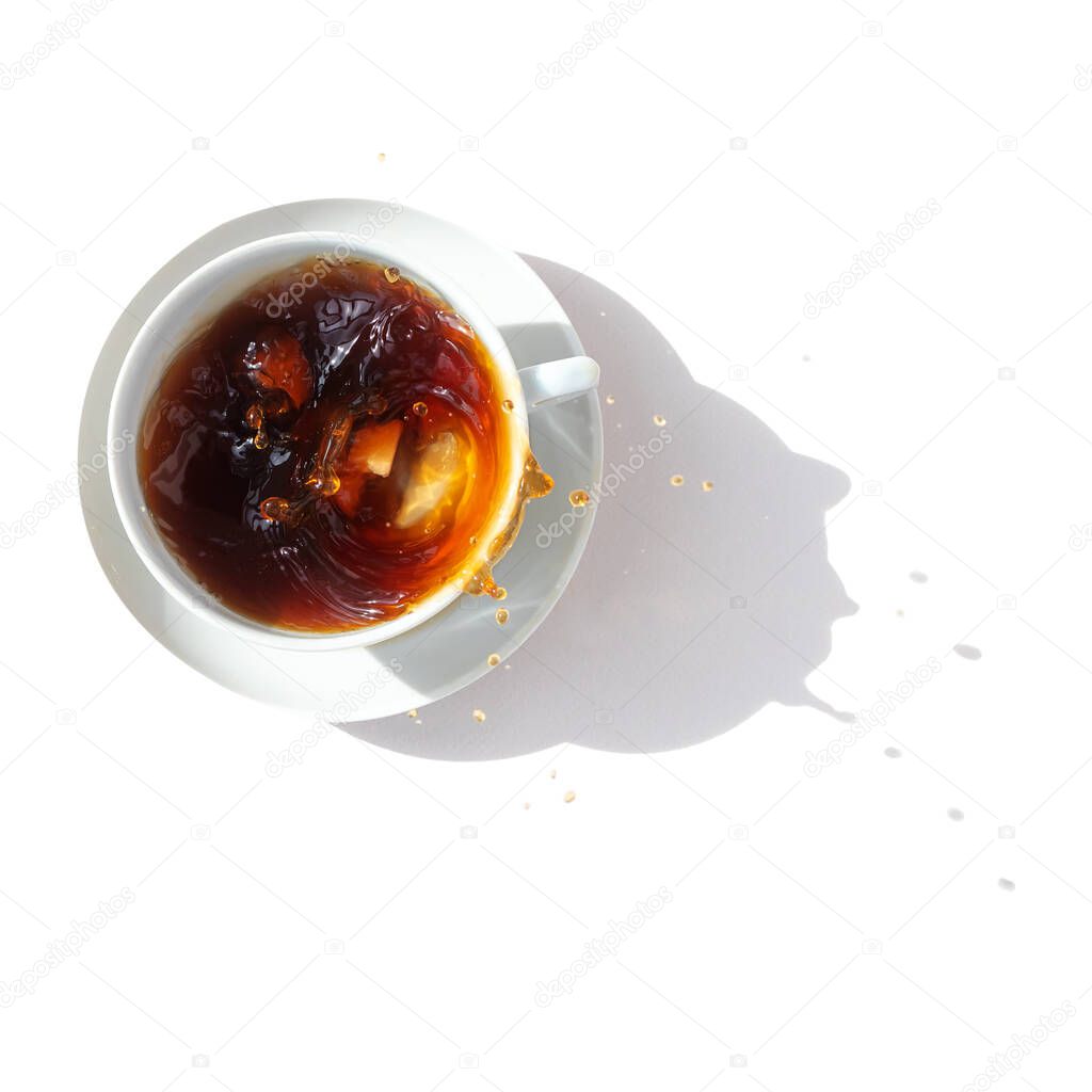 Black coffee in a white cup, top view. Sugar lumps are thrown into the cup, spectacular splashes are spilling out of the cup. White background. International coffee day.