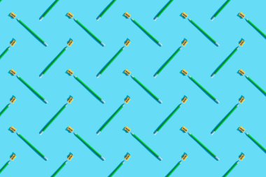 Mavi arka planda yeşil bir grafit kalem, silgi ve portakal açacağı var. Eğitim, iş, okul, ofis kavramı. Minimalizm, kopyalama alanı, desen.