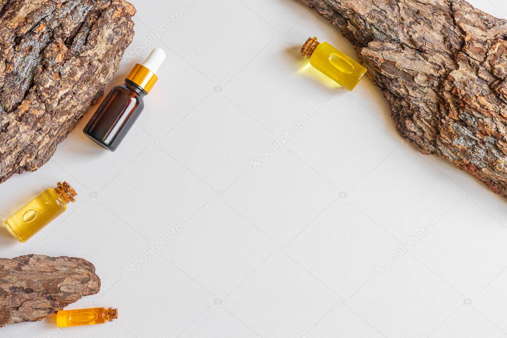Bottles of natural essential oil and tree bark with a beautiful texture. Neutral background. Concept for natural essences, organic cosmetics, aromatherapy, spa. Flat lay, copy space, top view.