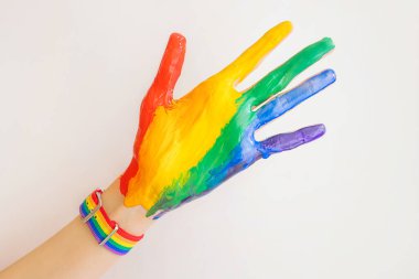 Bir kadının eli boya ve LGBT gökkuşağı renginde bir bilezik ile kaplıdır. Aşk kavramı, cinsel tolerans, LGBT gurur, eşcinsel ilişkiler, homoseksüellik..