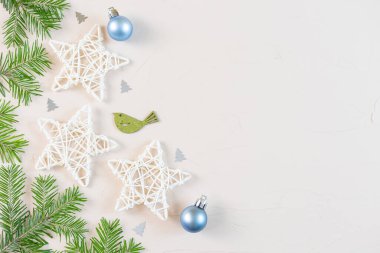 Yeni Yıl ve Noel dairesi pastel renklerle boyanmıştı: tahta dekoratif yıldızlar, köknar dalları, kuş ahşap heykelcikler, açık arkaplanda Noel ağacı oyuncağı topu. Kopyalama alanı, minimalizm, üst görünüm