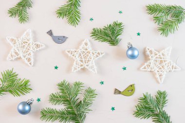 Yeni Yıl ve Noel dairesi pastel renklerle boyanmıştı: tahta dekoratif yıldızlar, köknar dalları, kuş ahşap heykelcikler, açık arkaplanda Noel ağacı oyuncağı topu. Kopyalama alanı, minimalizm, üst görünüm