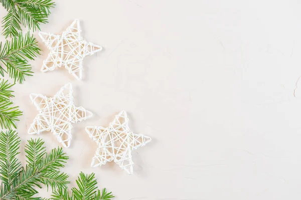 Yeni yıl ve yeni yıl dairesi pastel renkler içeriyordu: ahşap dekoratif yıldızlar, açık arkaplanda köknar dalları. Kopyalama alanı, minimalizm, üst görünüm