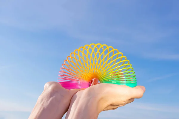 Juguete Arco Iris Plástico Las Manos Sobre Fondo Cielo Azul — Foto de Stock