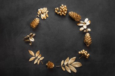 Yeni yıl dairesi altın ve siyah gölgelerle kaplıydı. Ladin dalları, yapraklar, koniler ve böğürtlenler altın boyayla boyanır. Şık bir Noel konsepti, kutlama. Üst görünüm, minimalizm, kopyalama alanı.