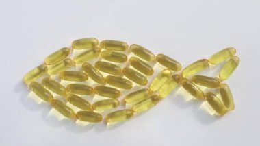 Omega3 vitamini konsepti, balık yağı. Kapsüller bir balık şeklinde serilmiştir. Boşluğu kopyala, minimalizm, üst görünüm.