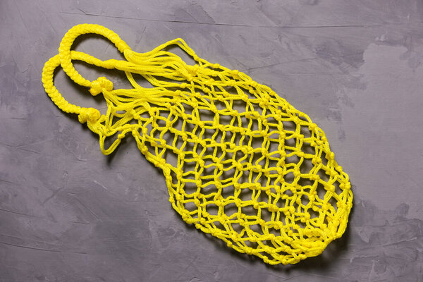 Yellow string bag on a gray background. Sustainability, zero waste, plastic free concept, vegetarianism, healthy food. Top view.