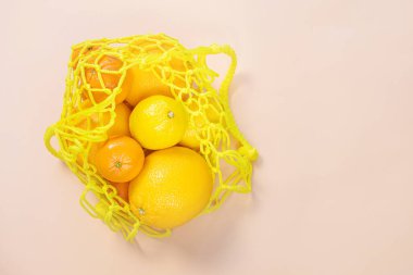 Portakallar, mandalinalar, sarı bir torba içinde limonlar. Citruslar, C vitamini sürdürülebilirlik, sıfır atık, plastiksiz konsept, vejetaryenlik, sağlıklı yiyecekler. Üst görünüm.