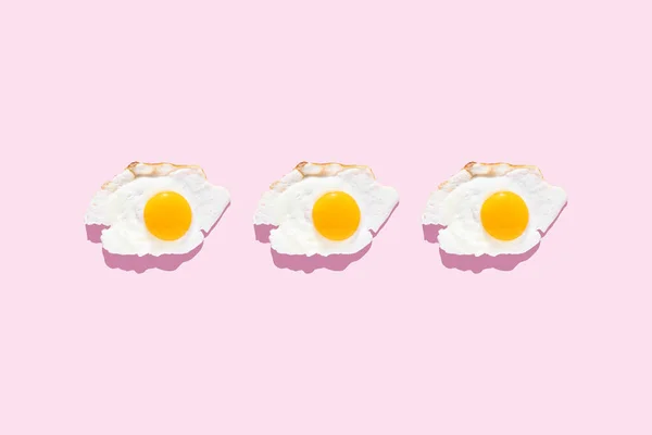 薄いピンクの背景に目玉焼き ミニマリスト トップビュー 朝食のコンセプト 揚げ料理 — ストック写真