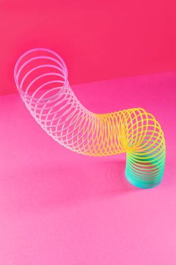 Pembe arka planda oyuncak plastik gökkuşağı. 90 'larda popüler olan oyun ve dublörler için renkli bir spiral. Minimalizm. Oyuncaklar, çocukluk kavramı. parlaklık.