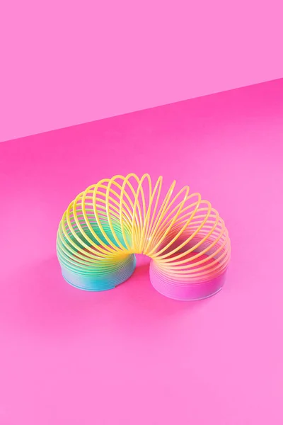 Pastel pembe arka planda oyuncak plastik gökkuşağı. 90 'larda popüler olan oyun ve dublörler için renkli bir spiral. Minimalizm. Oyuncaklar, çocukluk kavramı. parlaklık.