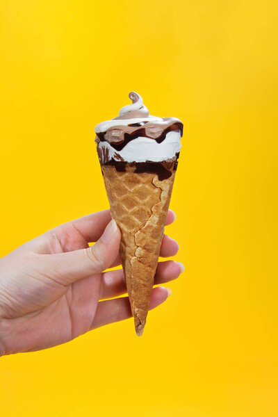 шоколадное мороженое в вафельном конусе на желтом фоне
.