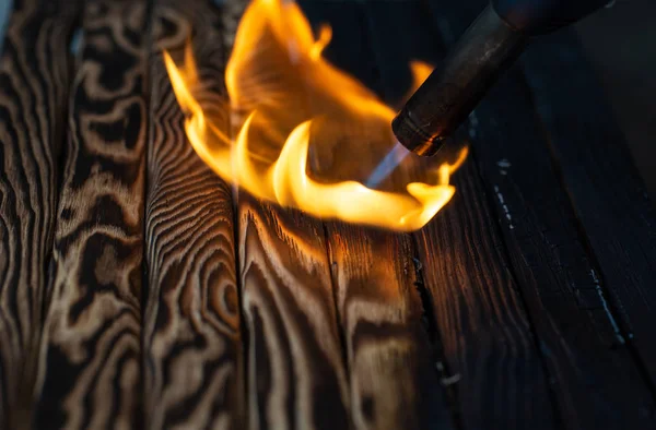 Verkohlte Holzbretter und Feuer. Hintergrund, Textur. Flamme. Holzverarbeitung. — Stockfoto