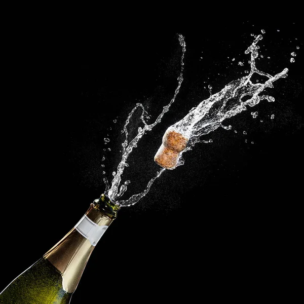 Opening a bottle of champagne. The celebration theme with splashing champagne isolated on black background. Traffics flying. — Stock Photo, Image