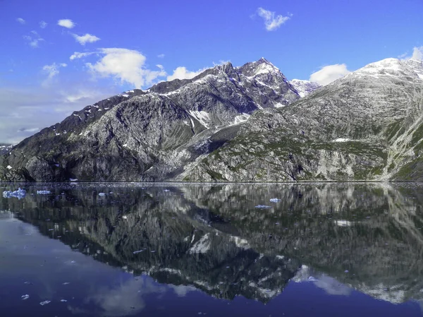 Alaska 'da yelken açarken, dağ manzarası buzullu suyu yansıtıyor.