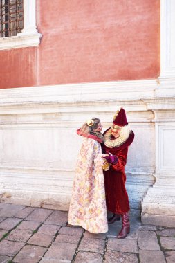 Venice, İtalya - 10 Şubat 2018: Çift Elizabethan yaka ve şapkalar ve Karnaval sırasında sokakta boyalı yüzler ile beyaz ve kırmızı kadife kostümleri