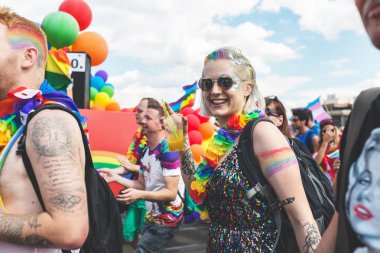 Prague, Çek Cumhuriyeti - 11 Ağustos 2018: katılımcıların yıllık Prag Gay gurur geçit töreni. Gökkuşağı bayrakları ve balonlar ile kalabalık. Genç sarışın kız gülümseyerek ve içme.