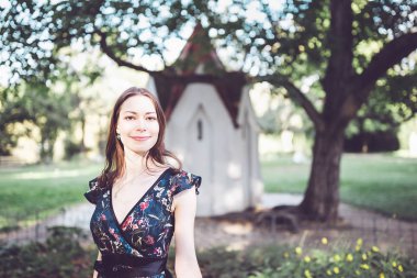 Portre parkta bir çiçek elbiseli neşeli iyimser esmer gülümseyen. 