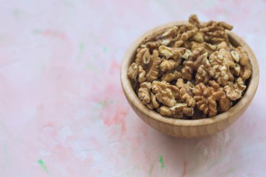 Ceviz taneleri, pembe backgrou ahşap bir kase içinde soyulmuş fındık