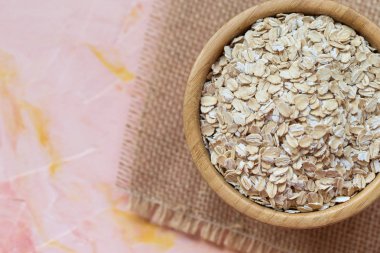 Pembe backgr bir ahşap kase çiğ yulaf ezmesi ya da yulaf gevreği