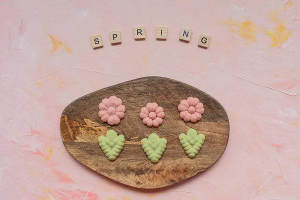 Άνοιξη cookies λέξη και λουλούδι σε ένα ξύλινο ταμπλό σε ένα ροζ backg — Φωτογραφία Αρχείου