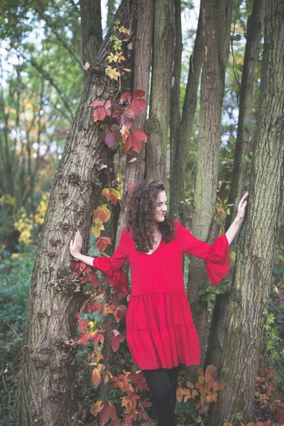 秋の公園で赤いドレスを着た美しい巻き毛の女の子 — ストック写真