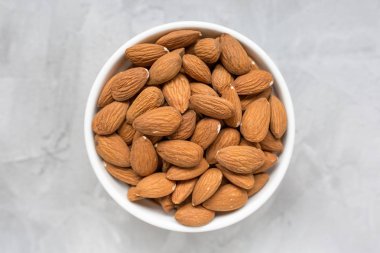 Gri bir arka plan üzerinde bir porselen kase çiğ badem