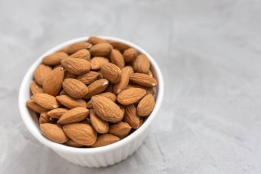 Gri bir arka plan üzerinde bir porselen kase çiğ badem