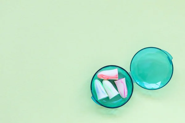 Earplugs in a box on the green background.