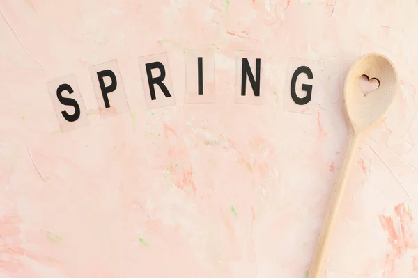 Wiosna słowo i mieszając łyżkę na różowym tle — Zdjęcie stockowe