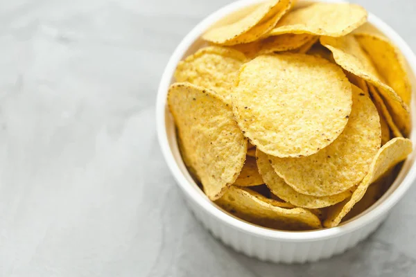 Tortilla corn chips in bowl on a gray background
