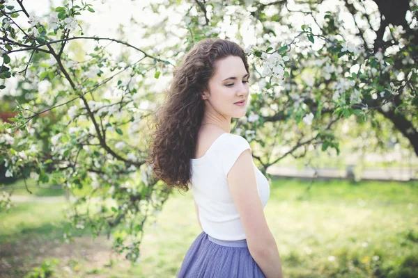 Joyeux jeune femme dans un t-shirt blanc sous l'arbre en fleurs . — Photo