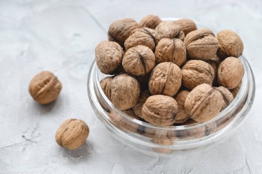 Walnuts in shell in bowl on gray background