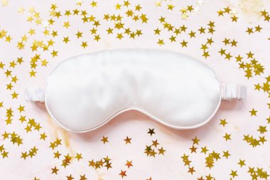 Pembe saten göz uyku maskesi ve altın yıldızlar.