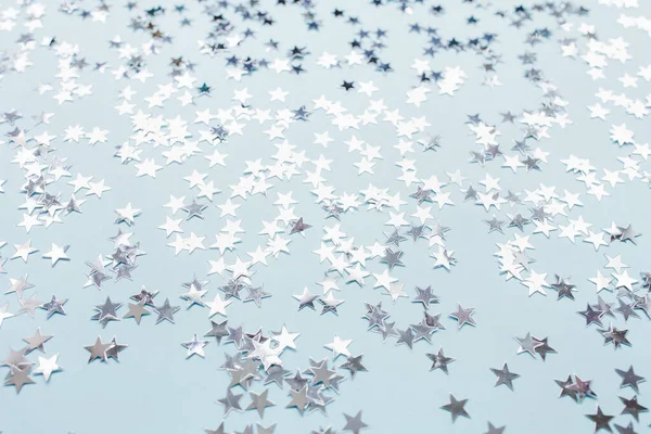 Silver foil confetti stars on blue background