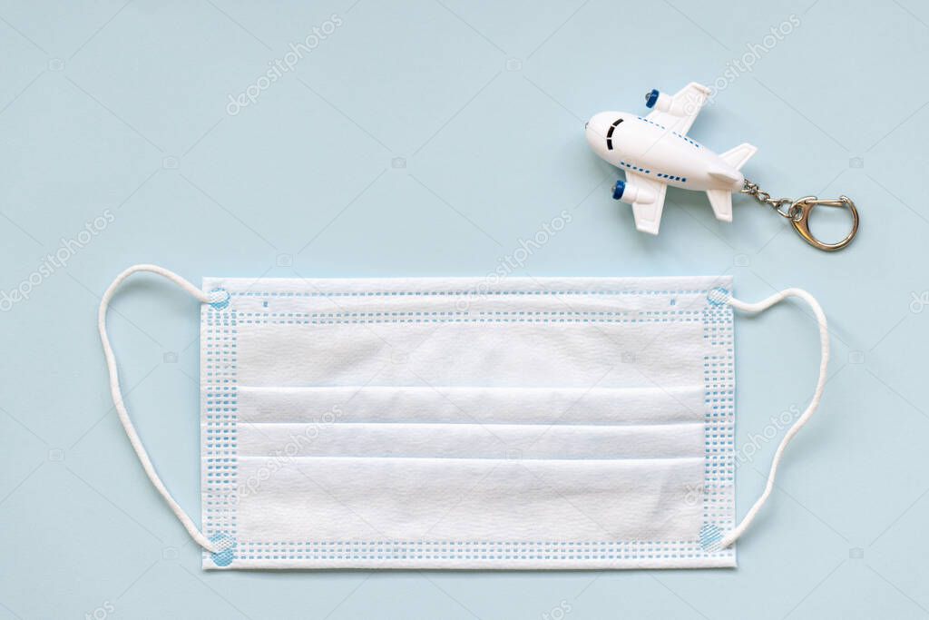 White surgical face mask and airplane on blue