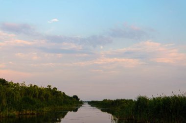 Sarı ve kırmızı günbatımı sakin bir nehir üzerinde akşam