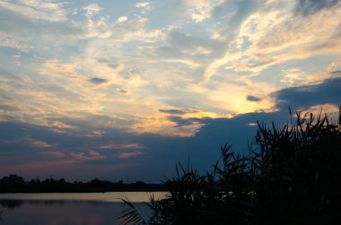 Sarı ve kırmızı günbatımı sakin bir nehir üzerinde akşam