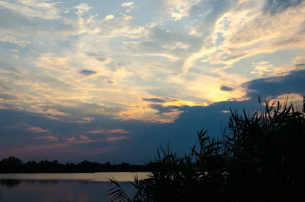 Sarı ve kırmızı günbatımı sakin bir nehir üzerinde akşam