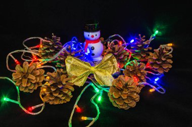 Noel ağacı garland, çam kozalağı, yılbaşı ağacı, kelebek, siyah bir zemin üzerine mum.