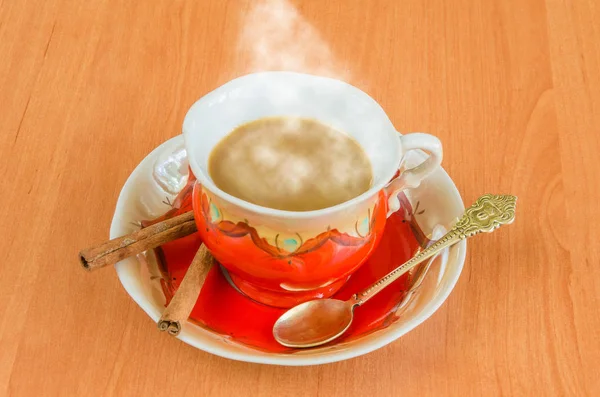 Bir fincan kahve ve kahve çekirdekleri ahşap zemin üzerine sütlü kahve.