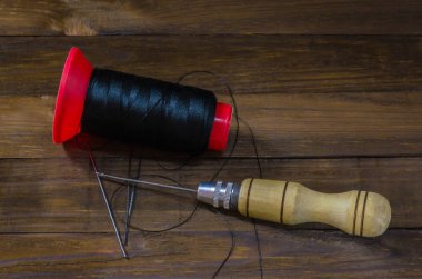 Naylon bir ahşap arka plan iş parçacığında yanında ayakkabı tığ.