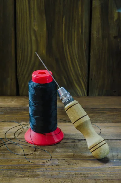 Naylon bir ahşap arka plan iş parçacığında yanında ayakkabı tığ.