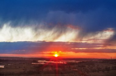 Altın gün batımında fırtına bulutları ve kırmızı güneş.