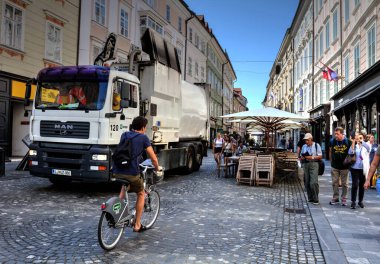 LJUBLJANA / SLOVENIA - AUGust 07: Çöp toplayıcı, 07.08.2019 'da Ljubljana' da, kafe masalarının yanında çalışırken sokak durumu. Slovenya 'ya Seyahat.